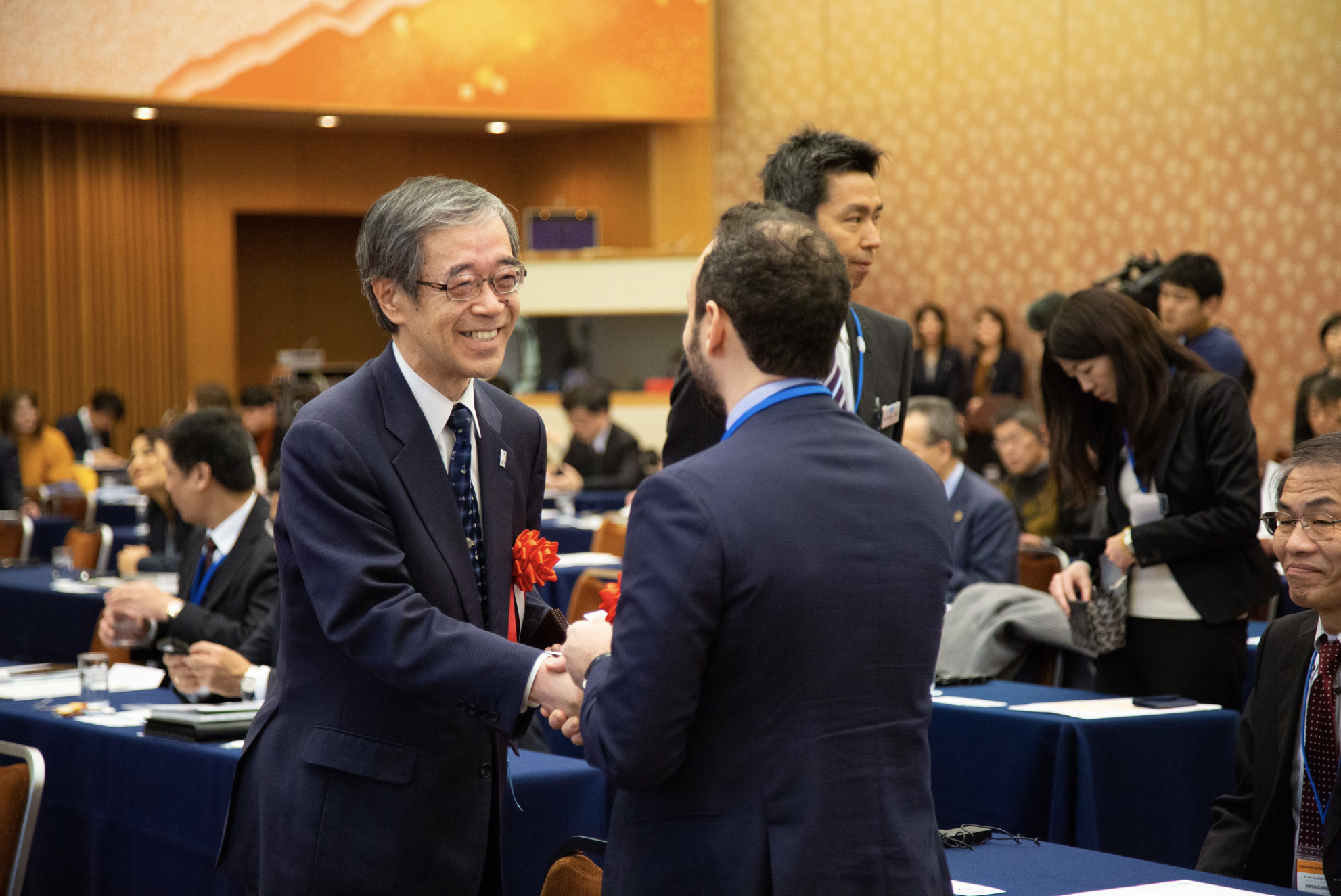 A participant smiles and greets another participant at the 2020 forum in Kobe, Japan 